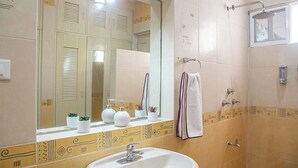 A bathroom with a sink, mirror, towel rack, shower, and decorative tiles. - Beautiful suite for up to 5 people, with a pool and private parking. (Mérida)