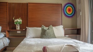 A hotel room with a bed, a bedside table, a wall-mounted decorative item, and a window with curtains. - Beautiful suite for up to 5 people, with a pool and private parking. (Mérida)