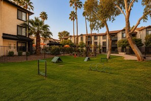 A well-maintained outdoor area with a grassy lawn, a play structure, and a row of residential buildings with balconies. - Stylish Suites: Pet-Friendly 2BR in Tempe | Near ASU w/ Pools & Gym (Tempe)