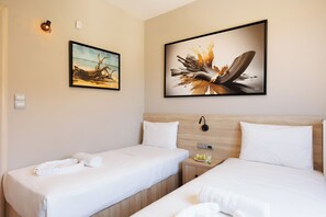 A hotel room with two single beds, a nightstand with a lamp, and two wall-mounted paintings. -     Lamon Villa | Elegant Seaside Escape with Private Pool (Myrthianos Plakias)
