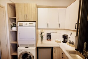 A compact laundry area with a washing machine, dryer, and a coffee maker on the countertop. -     Lamon Villa | Elegant Seaside Escape with Private Pool (Myrthianos Plakias)