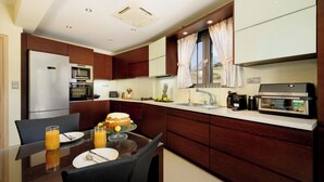 Eine moderne Küche mit Essbereich, ausgestattet mit Kühlschrank, Backofen und Kaffeemaschine.