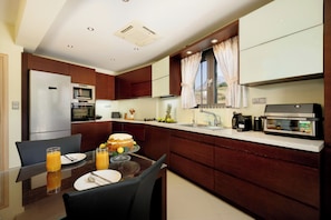 Eine moderne Küche mit Essbereich, ausgestattet mit Kühlschrank, Backofen und Kaffeemaschine.