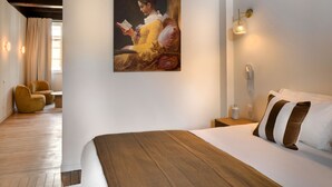 Et hotelværelse med en stor seng, et billede på væggen, et natbord, en lampe og et vindue med gardiner.