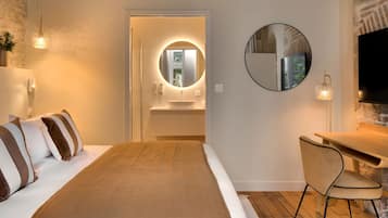 A hotel room with a bed, a desk, a round mirror, and a television.