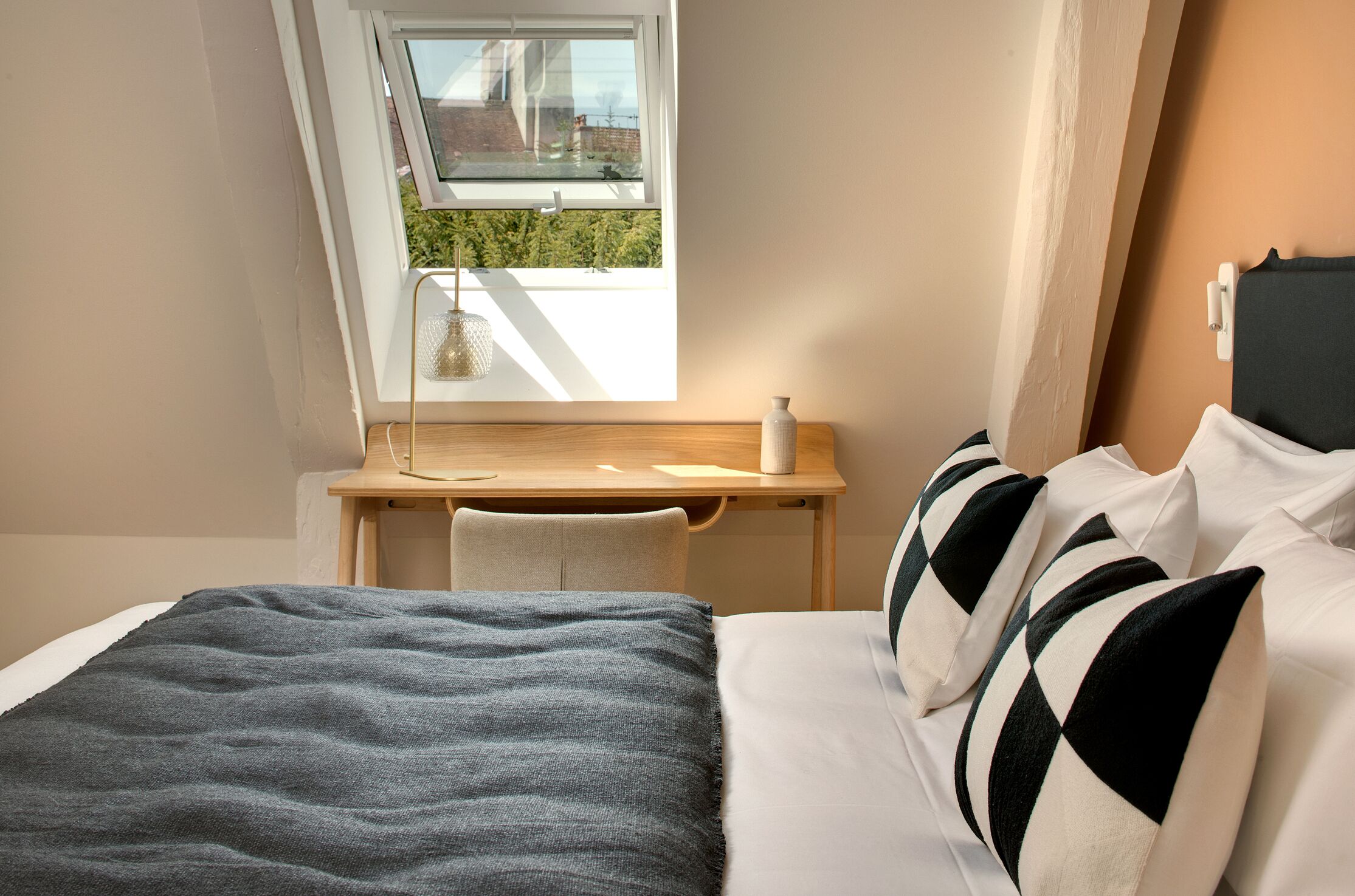 Un dormitorio con cama, escritorio y ventana.