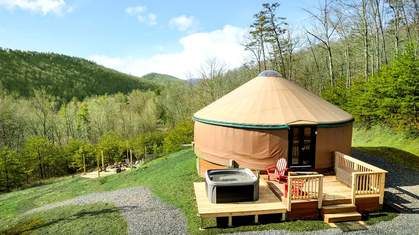 Een joert met een overdekt terras, een hottub en een terras met stoelen.