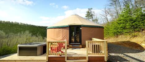A yurt with a covered entrance, a small porch, and a bench.