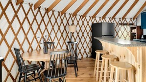 A dining area with a wooden table and chairs, a bar counter, and a kitchen area with a stove and cabinets.