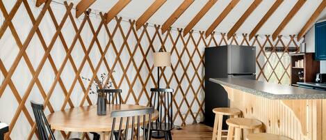 Un comedor con mesa y sillas de madera, una barra y una zona de cocina con estufa y armarios.