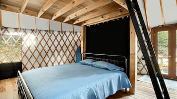Quarto com cama, escada e vista para o exterior.