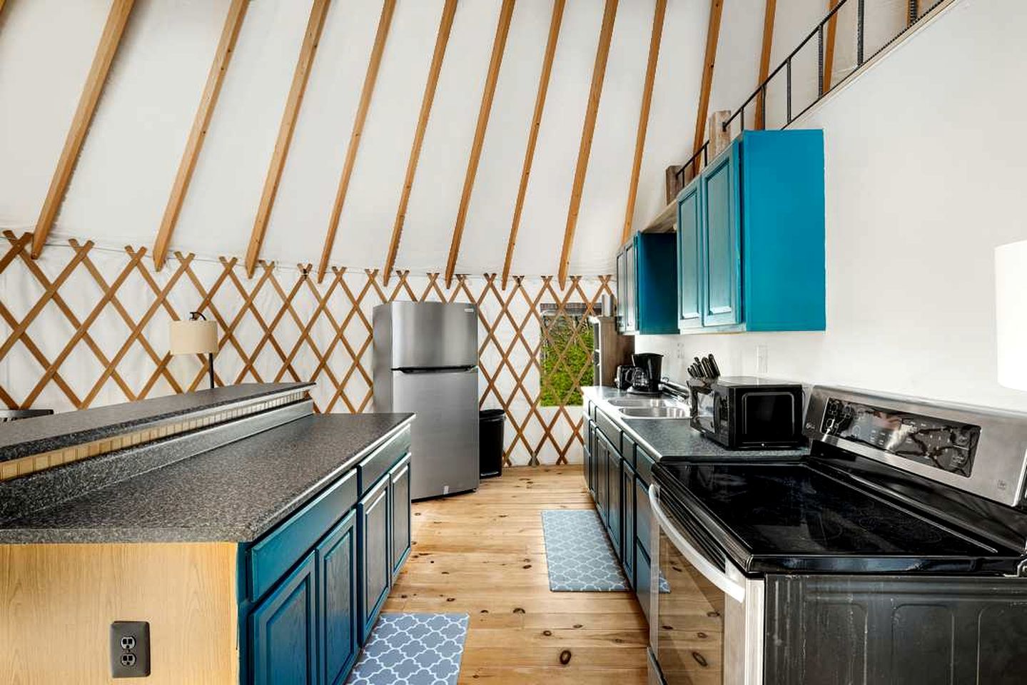 A compact kitchen with a refrigerator, microwave, and stove.