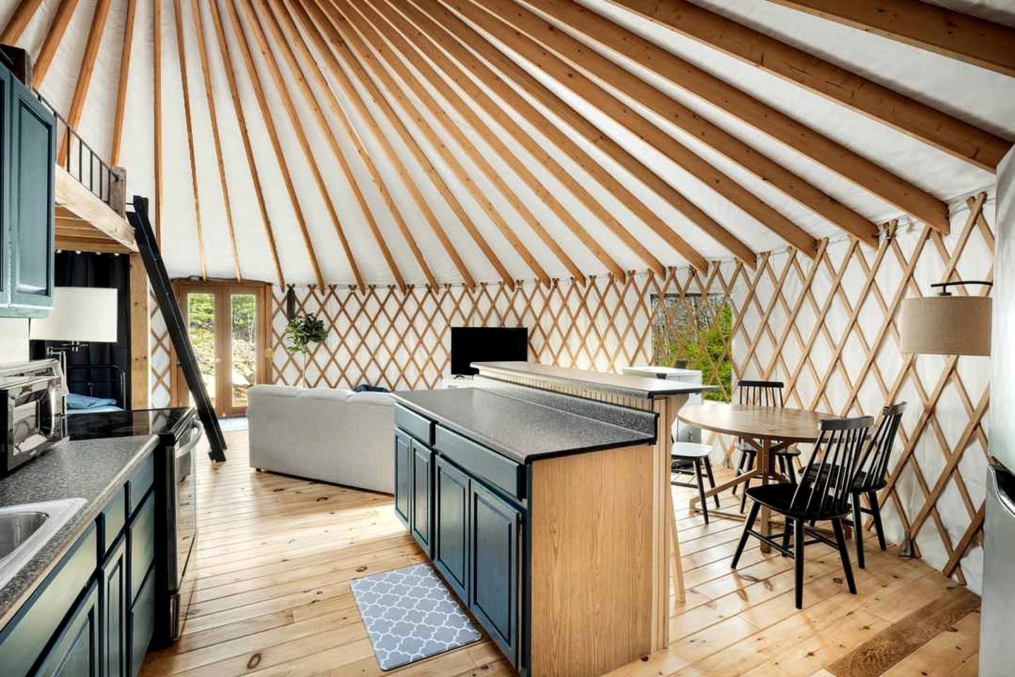 A yurt interior with a kitchen area, dining space, and a sofa.