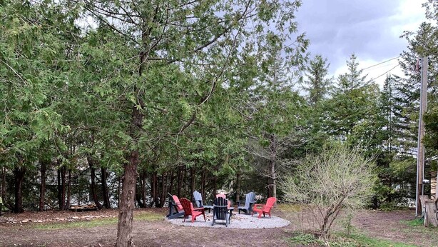 Ein Sitzbereich im Freien mit Adirondack-Stühlen, die um eine Feuerstelle angeordnet sind.
