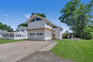 Une maison à deux étages avec un garage, une véranda et une pelouse bien entretenue.