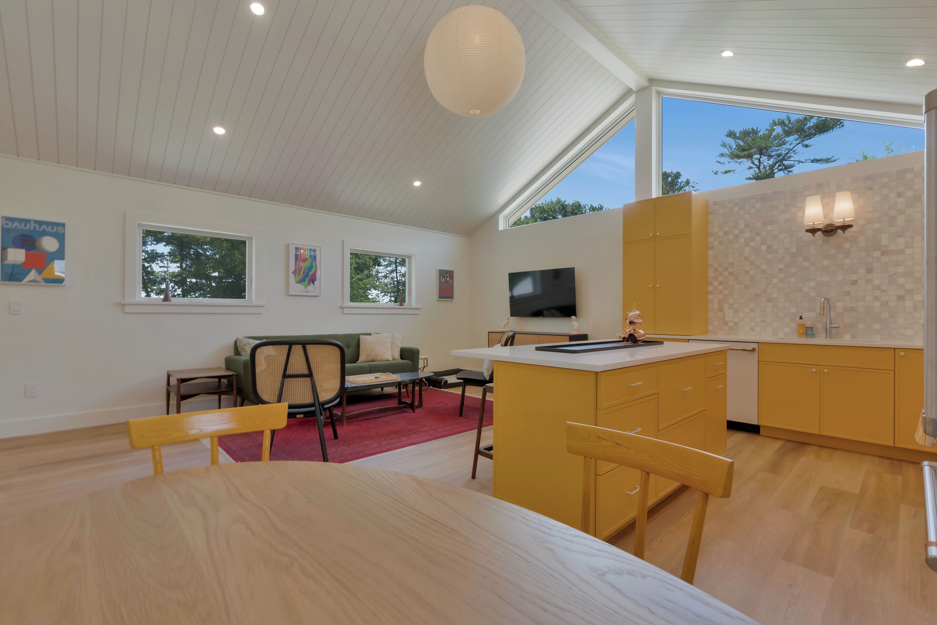 Eine moderne Küche mit Essbereich, Holzmöbeln und Kunstwerken an den Wänden.