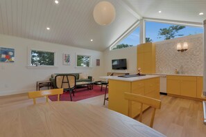 Eine moderne Küche mit Essbereich, Holzmöbeln und Kunstwerken an den Wänden.