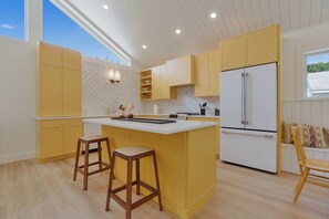 Une cuisine moderne avec un îlot central, des meubles de couleur jaune et un réfrigérateur blanc.