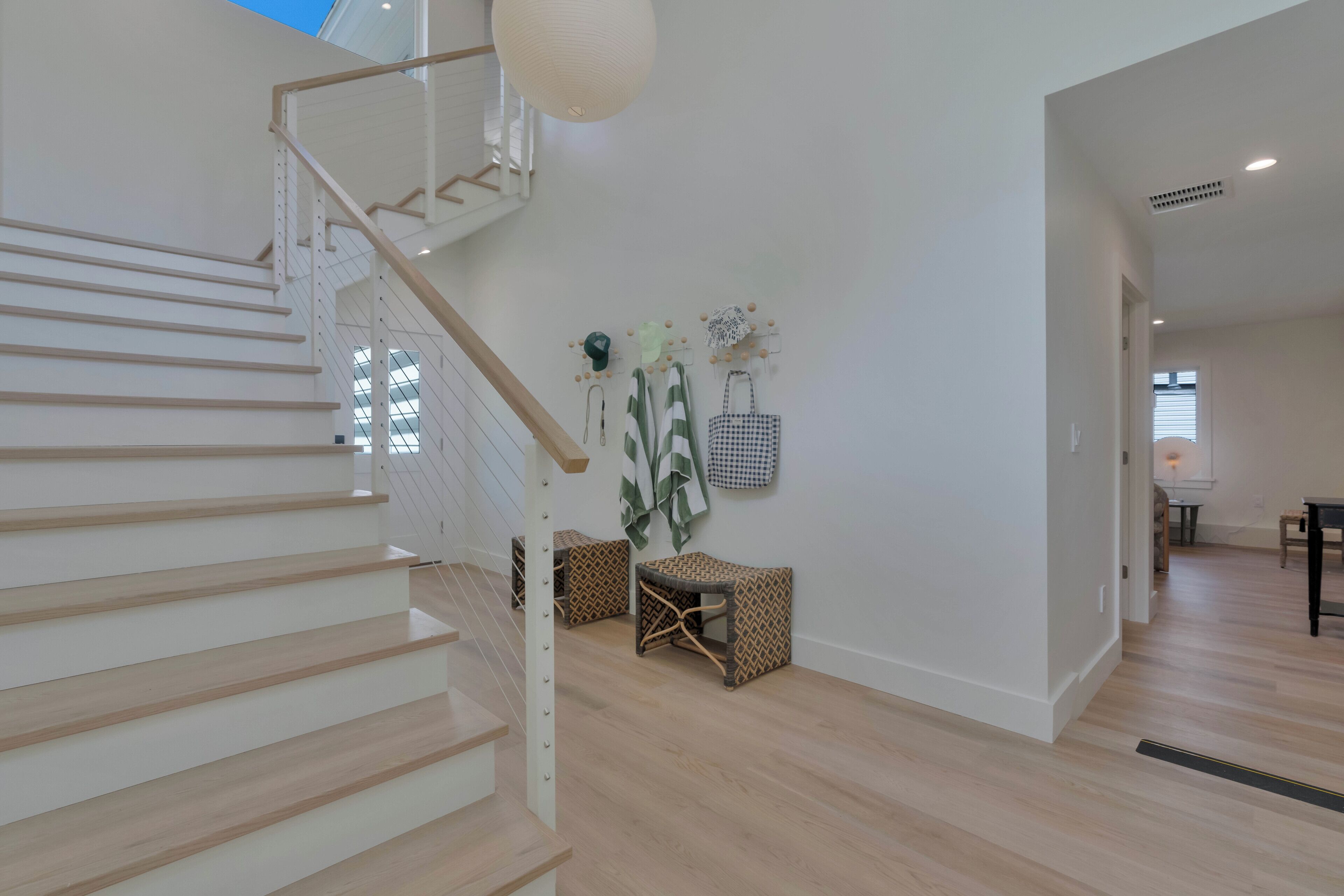 A modern interior with a wooden staircase, a wall-mounted plant, and a seating area with patterned cushions.