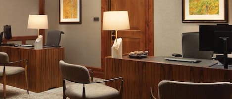 A reception desk with two chairs, a wooden door, and framed artwork on the walls.