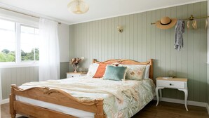 A bedroom with a wooden bed, a nightstand, a wall-mounted hat rack, and a window with curtains. - Amazing Vacation Rental with Fireplace in Daylesford, Victoria (Daylesford)