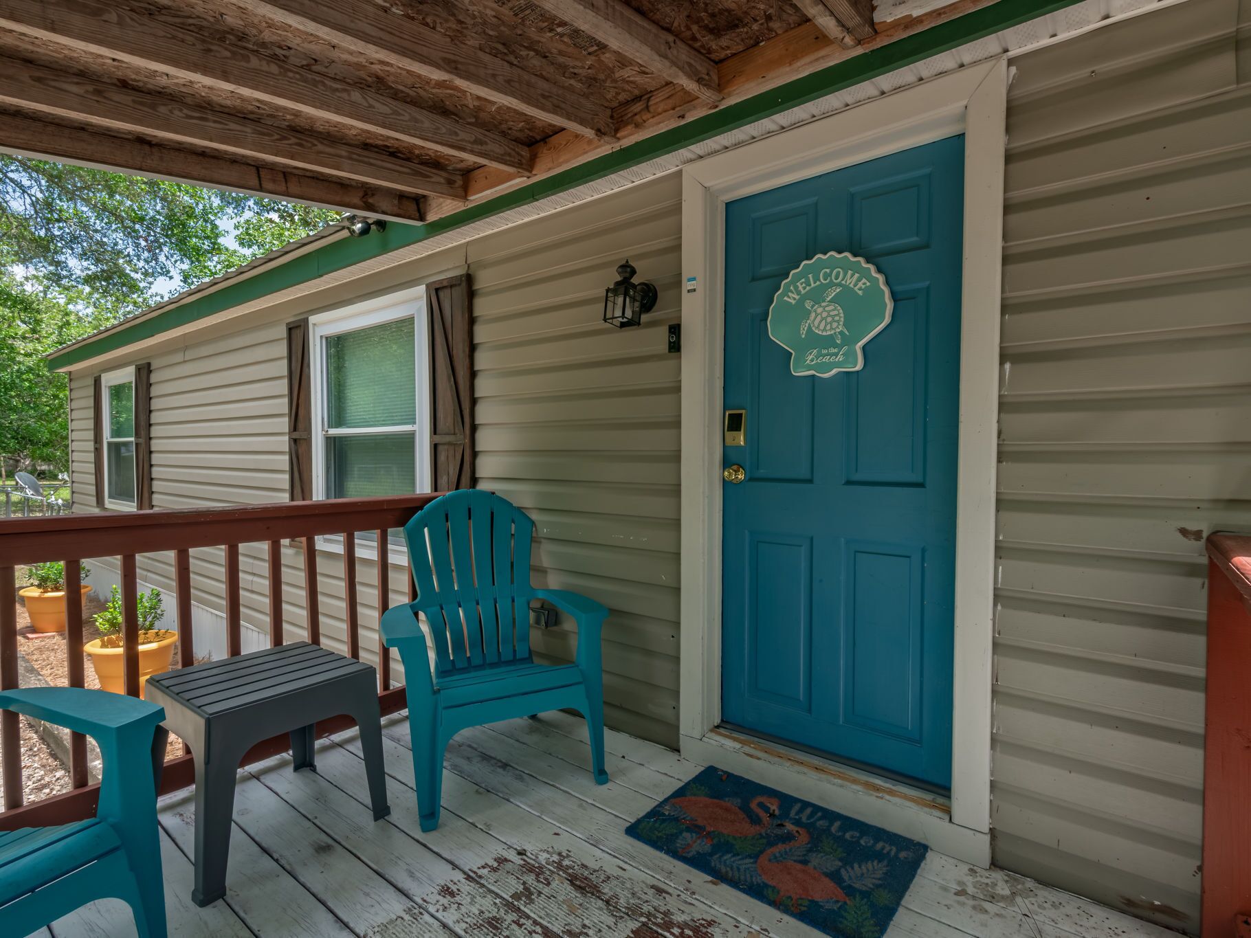 A porch with a blue door, a teal chair, and a bench.
