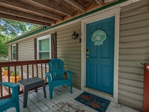 Eine Veranda mit blauer Tür, einem türkisfarbenen Stuhl und einer Bank.