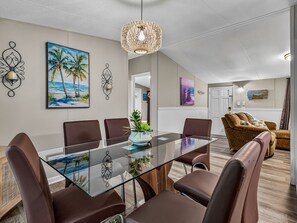 A modern dining area with a glass-top table, brown leather chairs, and decorative wall art. - Dickerson Bay Retreat w/ Boat Parking (Panacea)