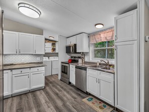 A modern kitchen with white cabinetry, a stainless steel sink, and a built-in oven.