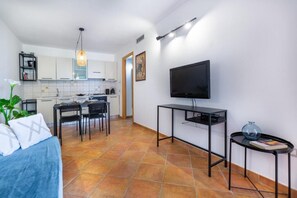 Un espace de vie compact comprenant un coin cuisine, un espace repas, un téléviseur et un lit.