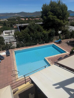 A swimming pool with a view of the surrounding landscape, including trees and distant hills. - Aetòs Home - Porto Pino (Porto Pino)