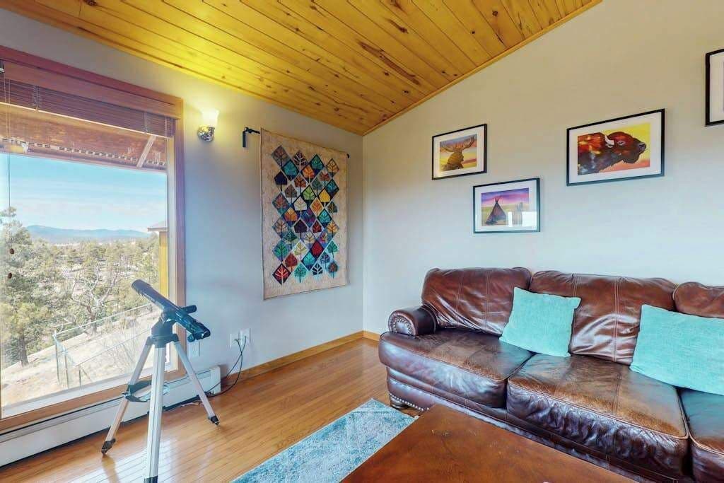 Um quarto com sofá de couro, um telescópio e obras de arte nas paredes.