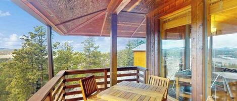 A wooden deck with a table and chairs, overlooking a scenic landscape.