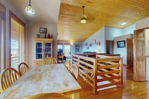 Ein Essbereich mit Holztisch und -stühlen, einer Holzbank und einer Decke mit Holzbalken.