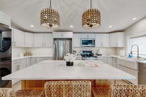 A modern kitchen with white cabinetry, a central island, and two hanging wicker pendant lights. - Two Bit Cabin - Secluded Cabin • Hot Tub & ATV Trails (Deadwood)