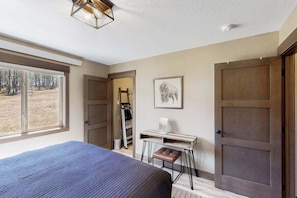 A bedroom with a bed, desk, and wardrobe. - Rost Place Round-Up - Dog-Friendly Cabin • Mtn Views & BBQ (Sturgis)