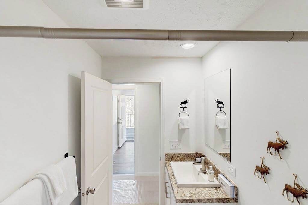Une salle de bain avec un lavabo blanc, un miroir et un porte-serviettes.
