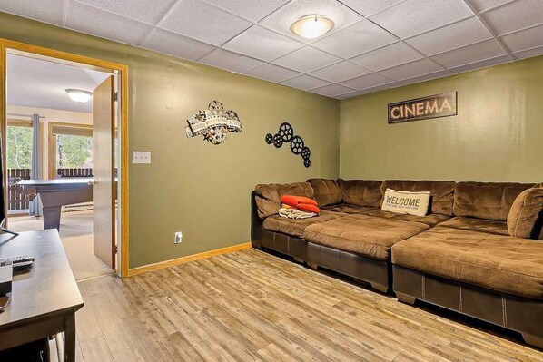 Una sala de estar con un sofá seccional, una mesita de centro y un letrero en la pared que dice 'CINEMA'.