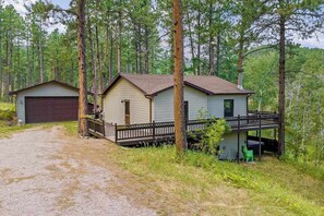 A cabin with a garage, a covered porch, and a small outdoor seating area.