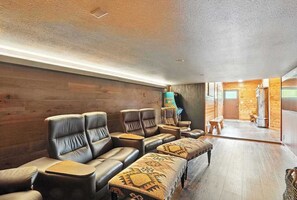 Um quarto com parede de madeira, assentos de couro, uma mesa pequena e um tapete estampado.