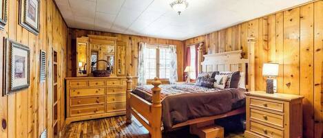 A wooden-paneled bedroom with a bed, dresser, and nightstand.