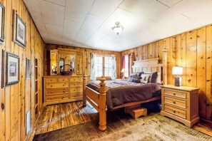 A wooden-paneled bedroom with a bed, dresser, and nightstand. - Big Bear Cabin - Dog-Friendly Cabin • Great Location (Woodland Park)