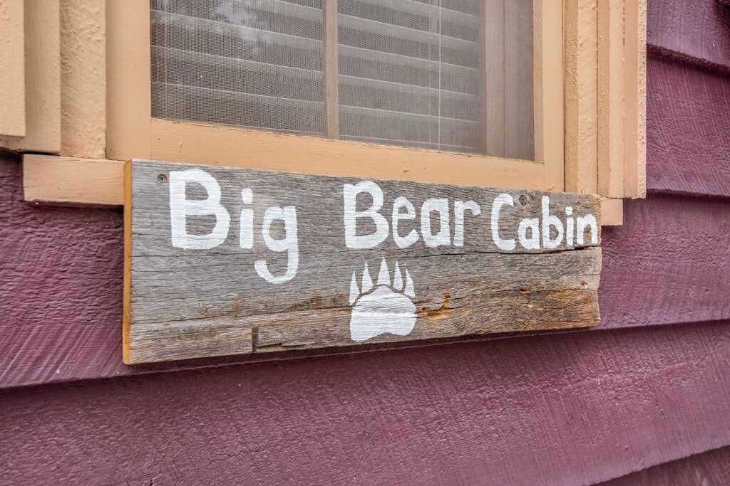 Ein Holzschild mit dem Schriftzug 'Big Bear Cabin' und einer Bärenpfote.