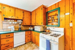 A kitchen with wooden cabinets, a dishwasher, a stove, and a microwave. - Big Bear Cabin - Dog-Friendly Cabin • Great Location (Woodland Park)