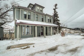 Ein zweistöckiges Haus mit einer Veranda und einem mit Schnee bedeckten Dach.