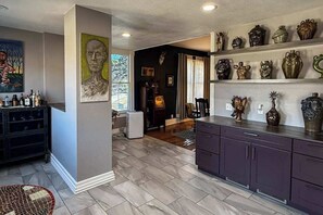 Une cuisine moderne dotée d’un îlot central, de meubles de rangement aux couleurs sombres et de divers objets décoratifs disposés sur des étagères.