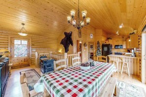 Ein Holzblockhaus-Interieur mit Essbereich, Küche und einem aufgehängten Tierkopf als Dekoration.