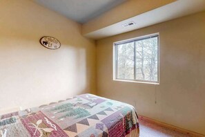 A bedroom with a bed, a window, and a wall-mounted sign.