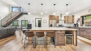 Una cocina amplia con una isla grande, armarios de madera y una escalera moderna.