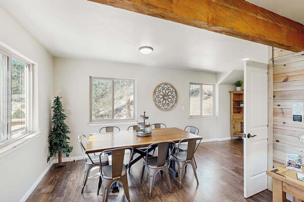 A dining area with a wooden table and metal chairs, a Christmas tree, and a decorative wall piece.